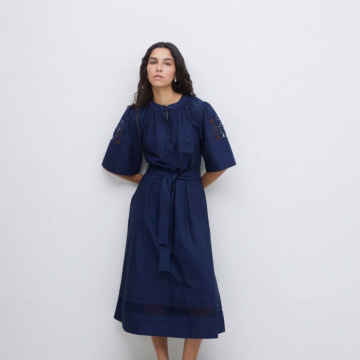 Navy midi dress with short sleeves, button front, self-tie belt, and lace detailing at shoulders and hem.
