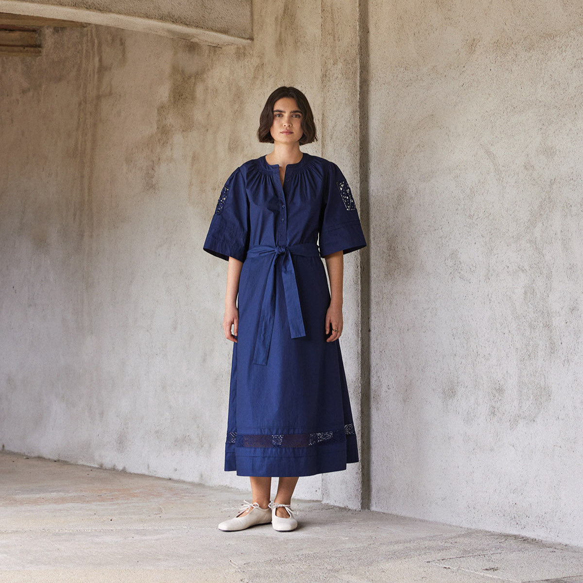 Navy midi dress with elbow-length sleeves, a self-tie belt, and lace detailing at the shoulders and hem.