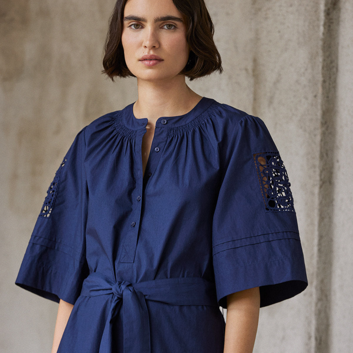 Navy blue cotton dress with elbow-length sleeves, a self-tie belt, and lace inserts at the shoulders.