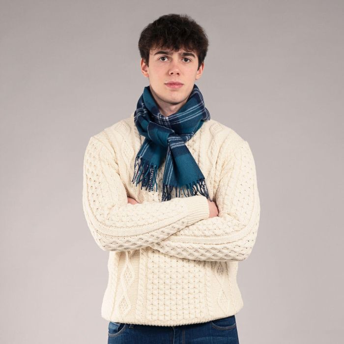 Teal and white plaid wool scarf, fringed edges, worn by a person in a cream cable knit sweater.