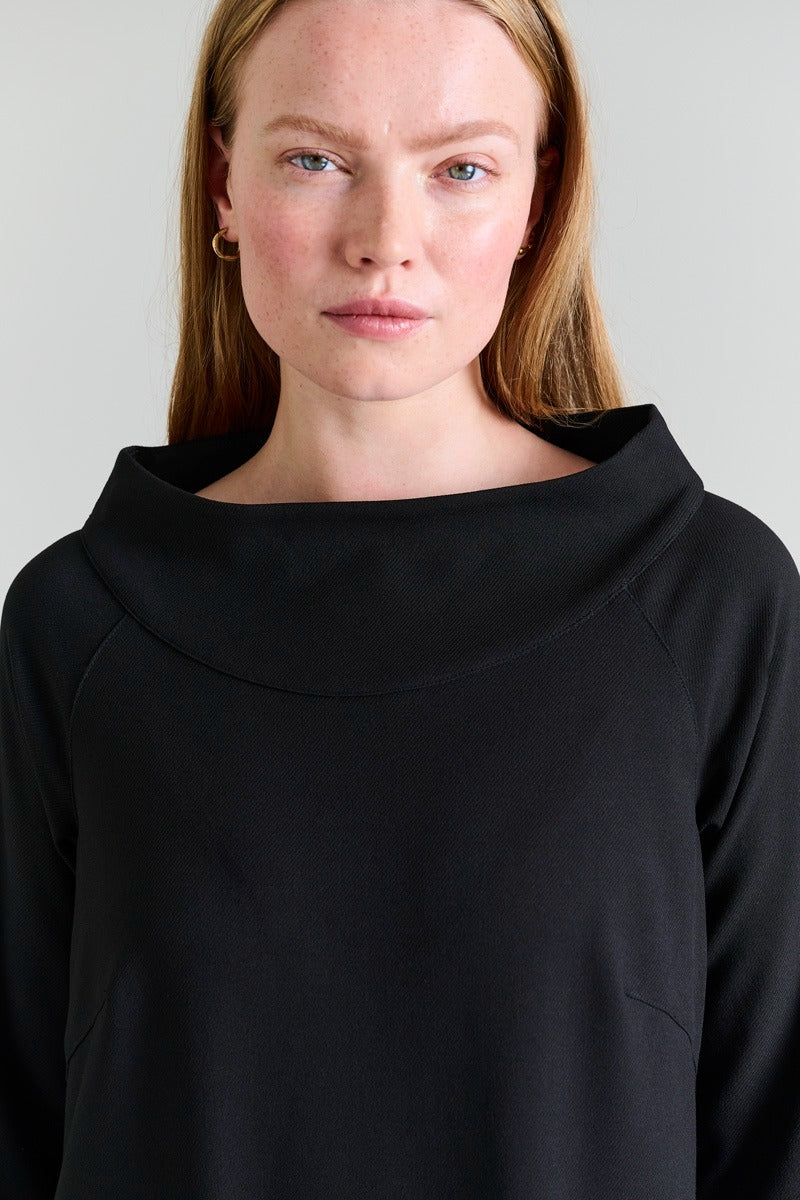 Person wearing a black hoodie against a plain background
