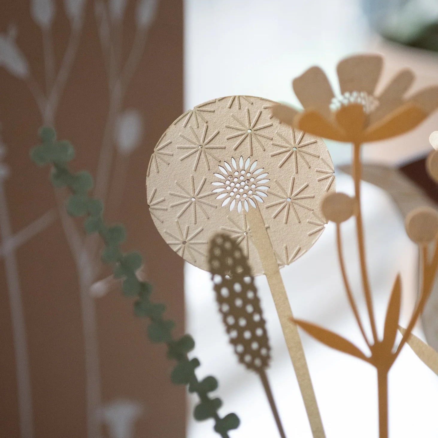 Intricate beige paper dandelion and flower design with cut-out details.