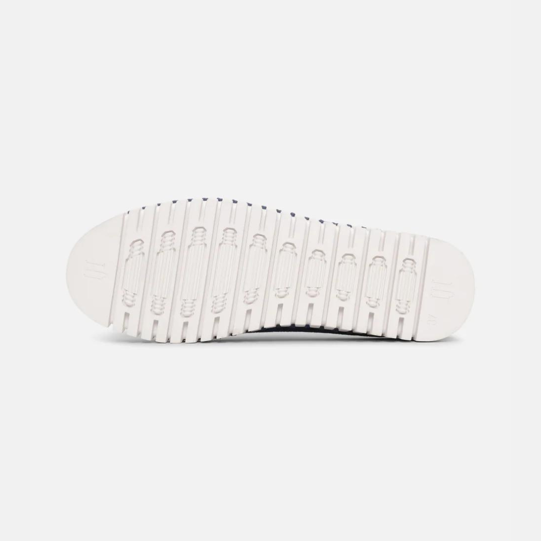 Navy blue shoe sole with off-white textured tread, showing repeating oval patterns and subtle branding.