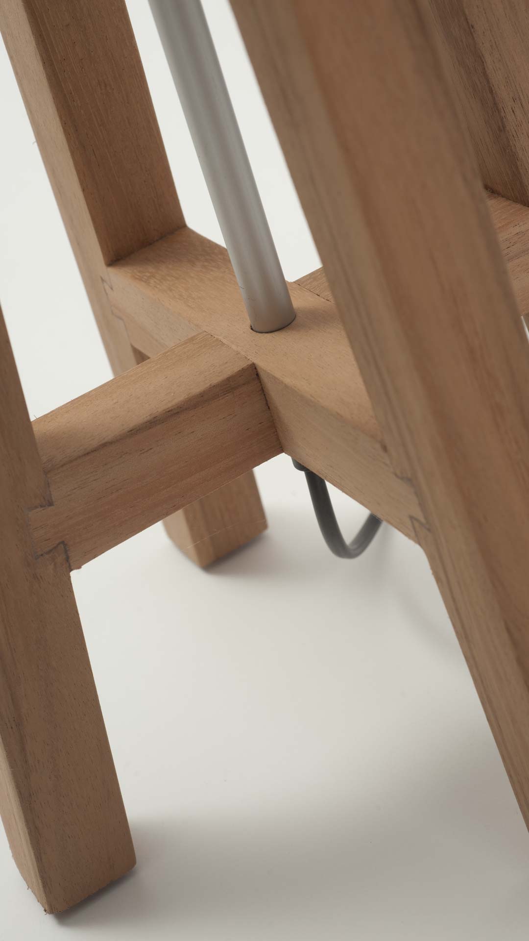 Close-up of a wooden lamp base with a silver metal center pole.