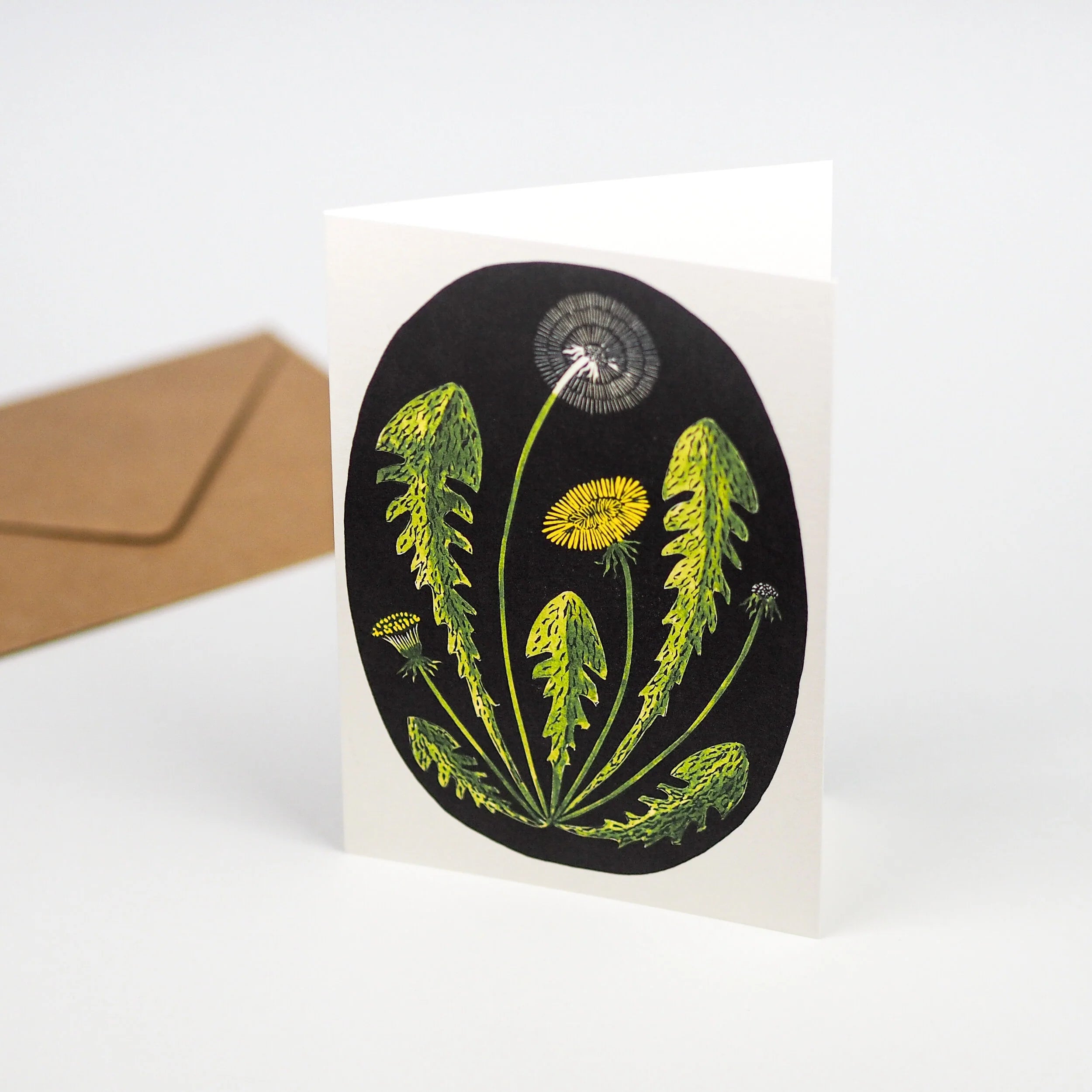 Greeting card featuring a stylized illustration of dandelions in various stages of bloom, set against a black circular