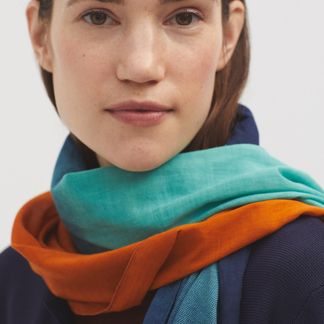 Teal, orange, and blue ombre scarf draped around a woman's neck.