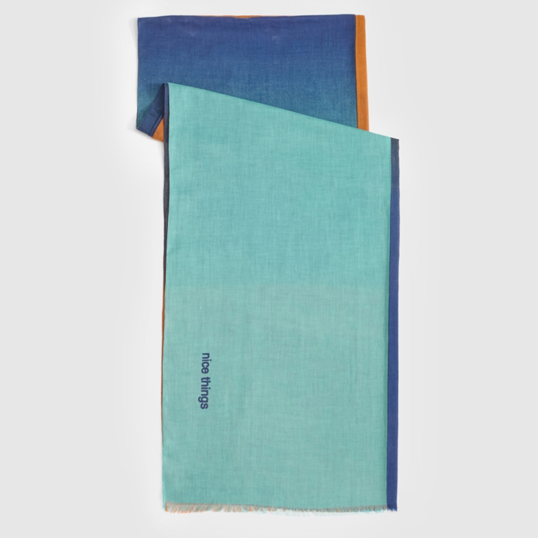 Ombre scarf in teal, blue, and orange with "nice things" embroidered on the teal section.