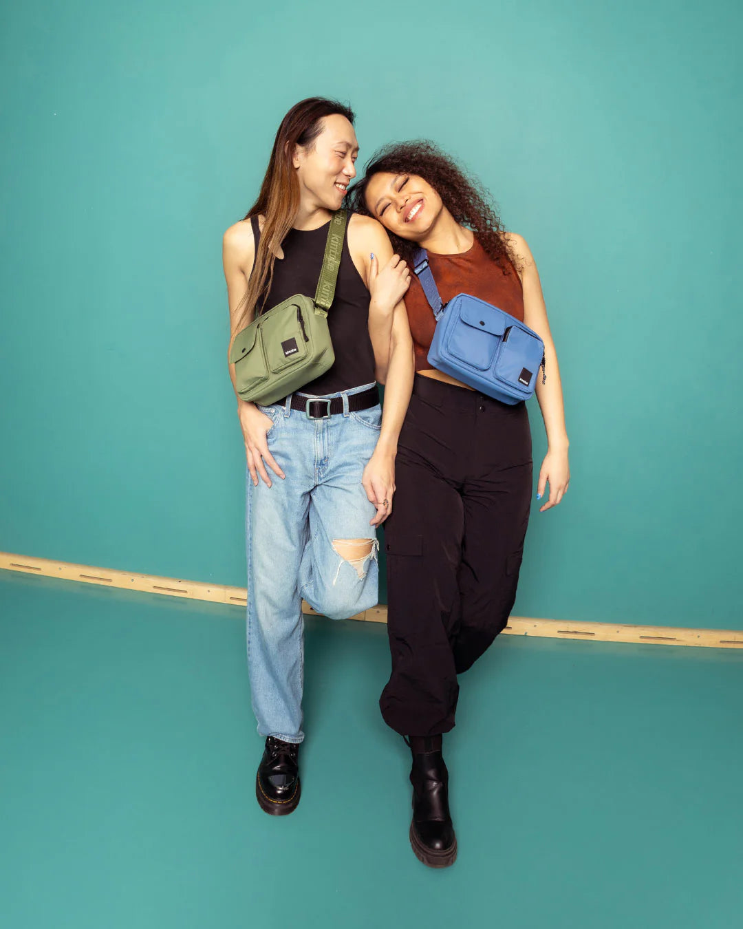 Two crossbody bags; one olive green, one blue. Both bags feature multiple compartments and adjustable straps.