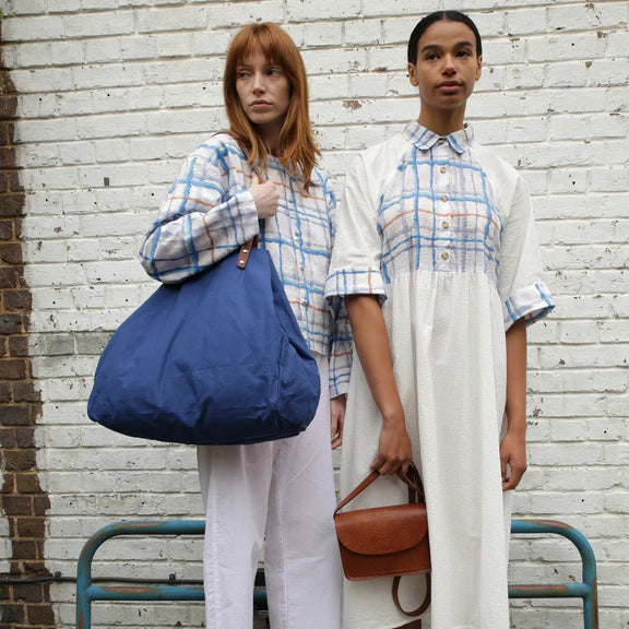 Large cobalt blue tote bag and small brown leather crossbody bag.