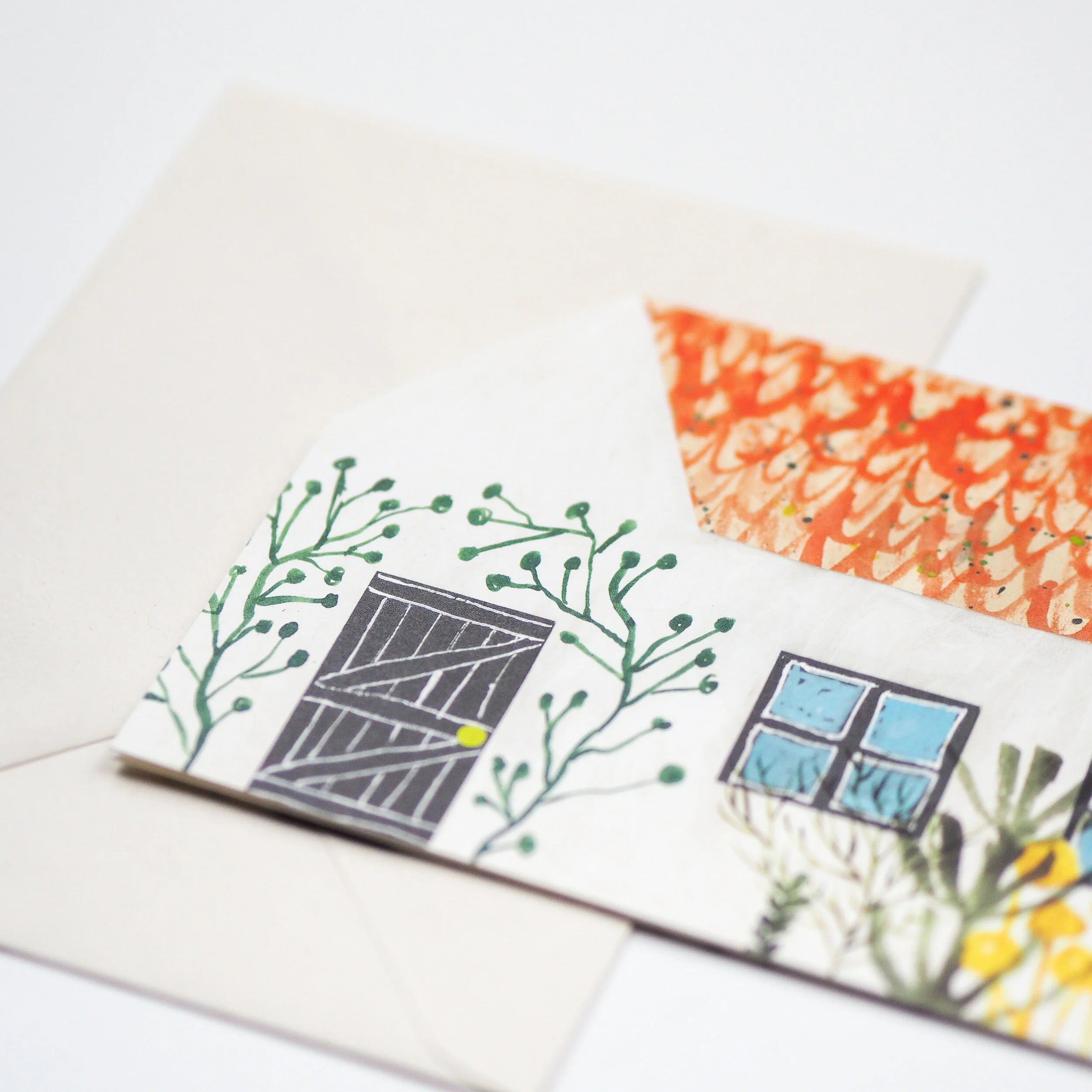Illustrated envelope featuring a house with a dark gray door, light blue window, orange roof, and green foliage.
