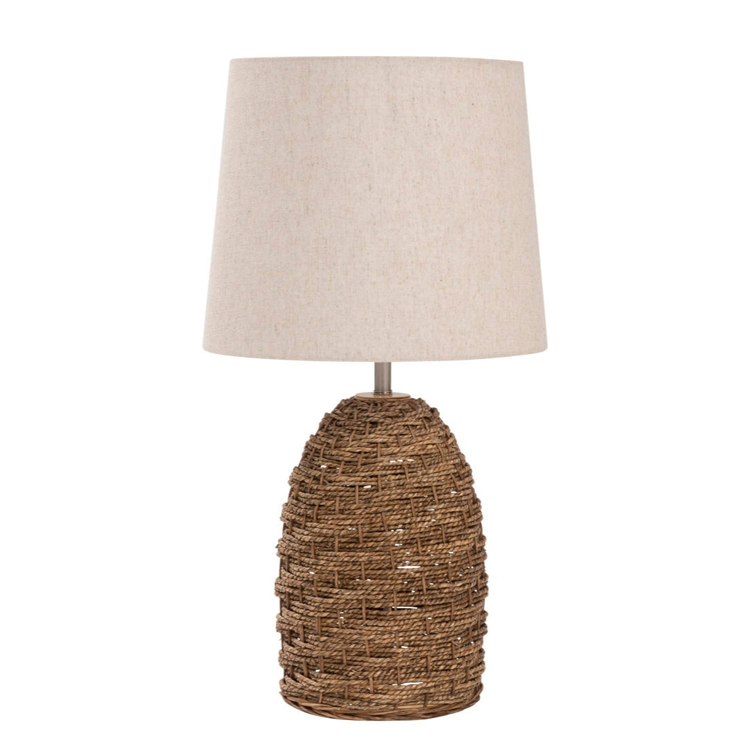 Table lamp with a beige linen shade and a brown woven seagrass base.