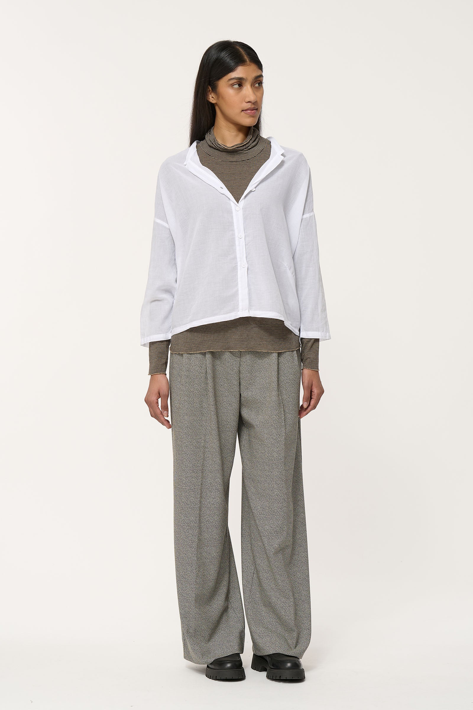White button-up shirt with a relaxed fit and three-quarter sleeves, layered over a brown striped top.