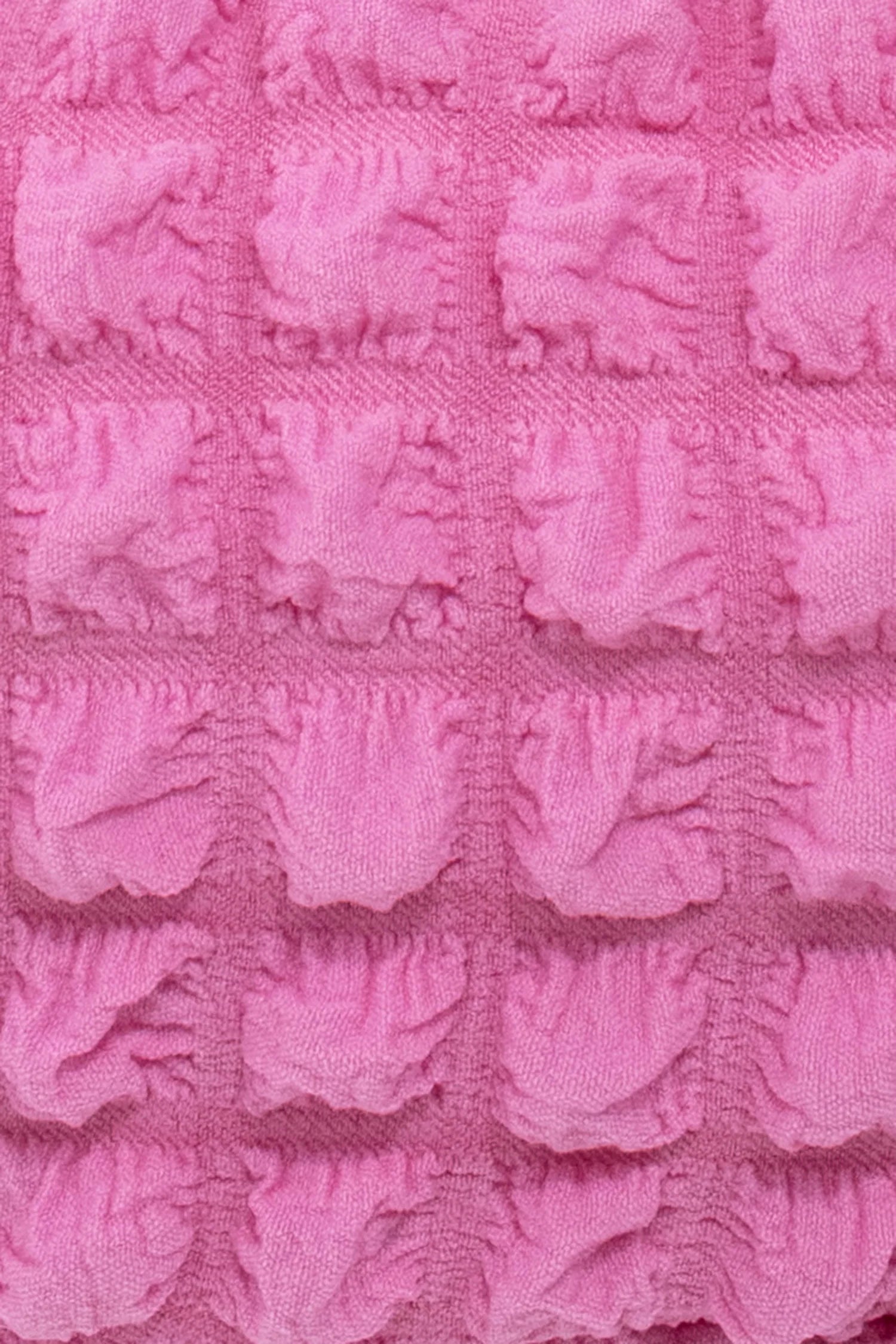 Close-up of pink textured fabric with a repeating pattern of raised, flower-like shapes.