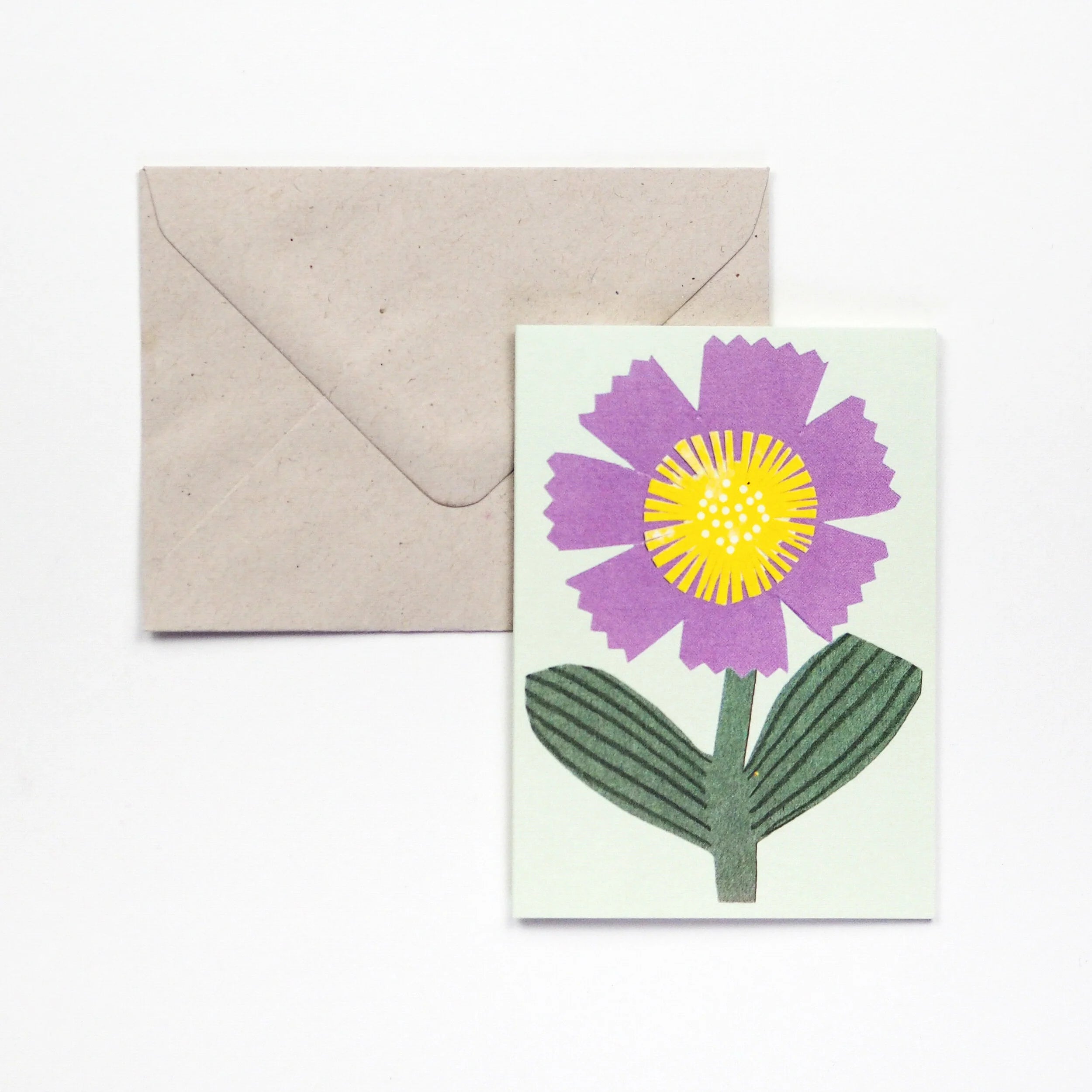 Greeting card featuring a purple flower with a yellow center and green leaves, shown with a kraft envelope.