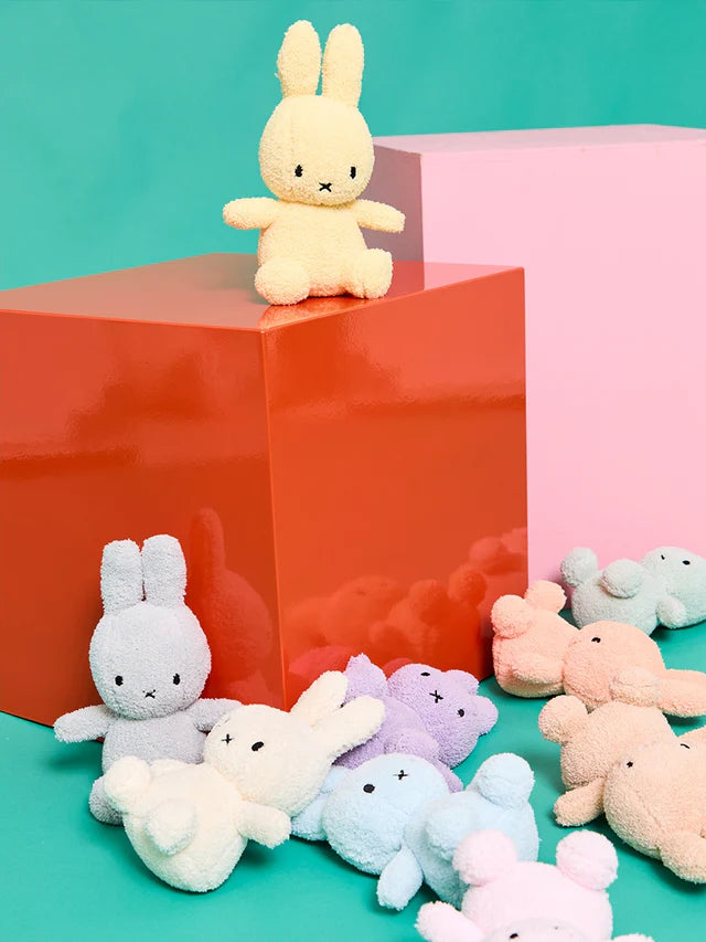 Colorful plush bunnies on a teal and pink background