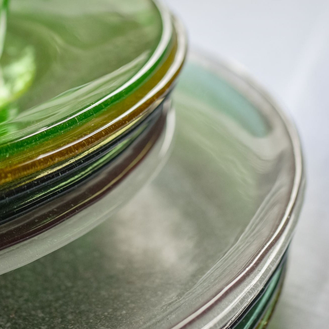 Stack of glass plates, top plate is green, others are clear and slightly tinted.