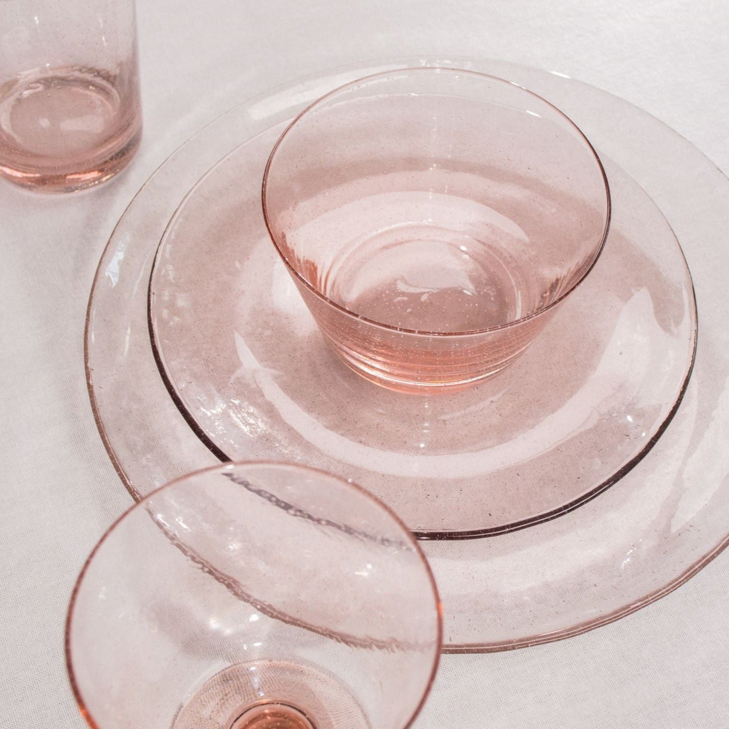 Pink glass bowl and plates, nested, with textured surface.