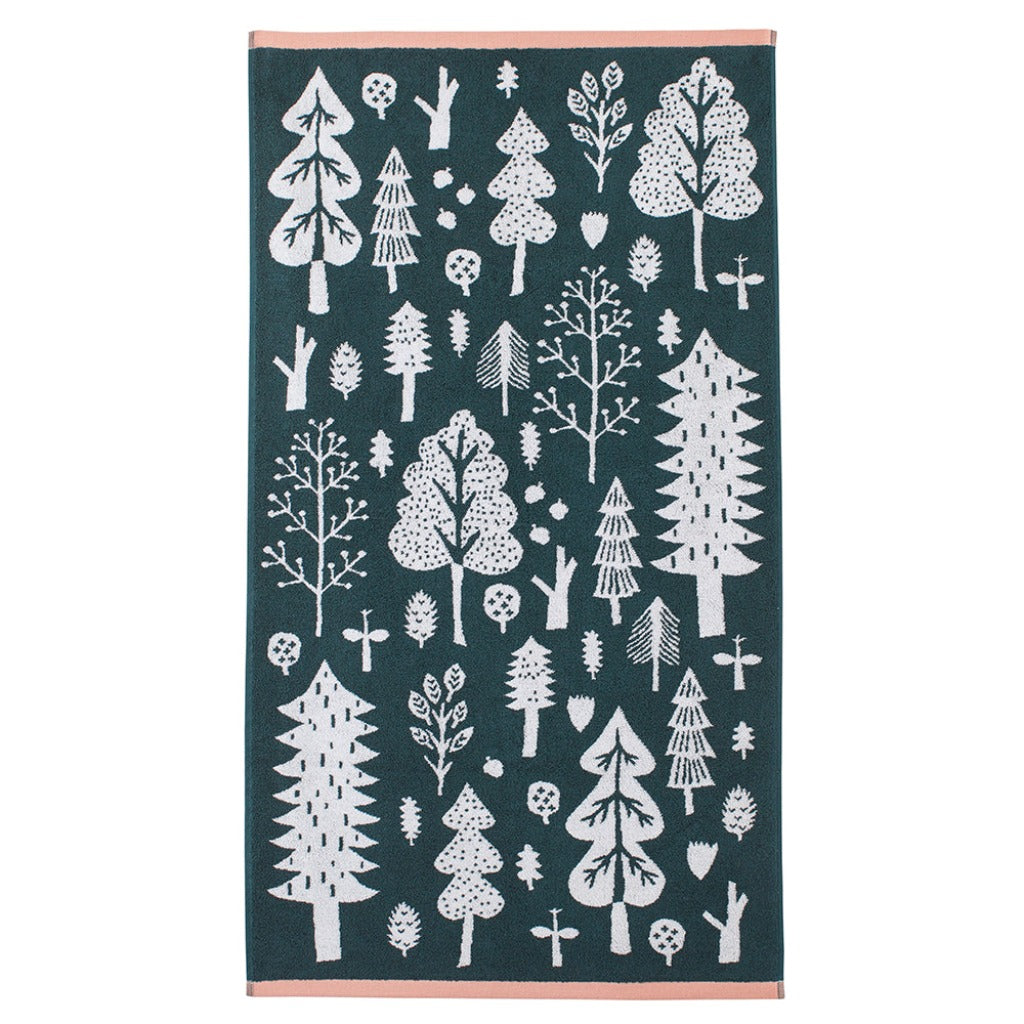 A green Donna Wilson towel featuring white trees and plants, with a pink border.
