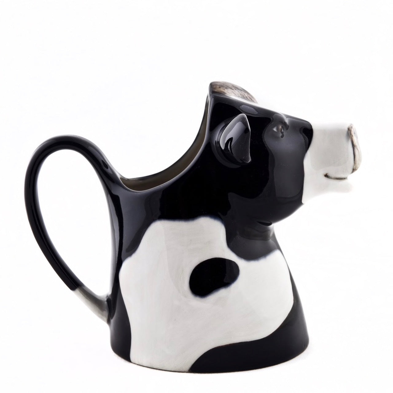 Black and white ceramic creamer shaped like a cow's head, featuring a handle and spout.