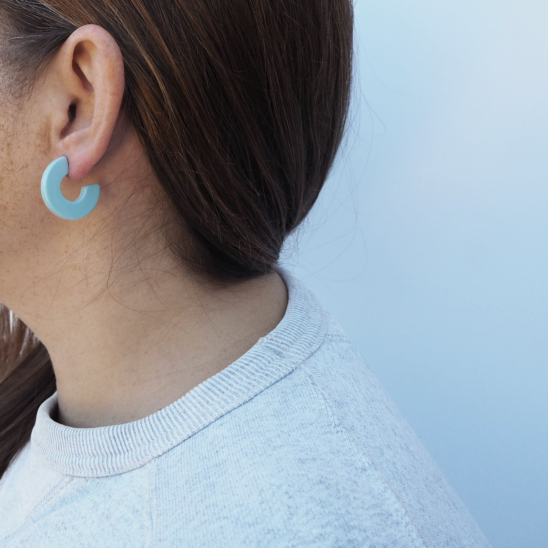 Pair of light blue, matte, C-shaped hoop earrings.