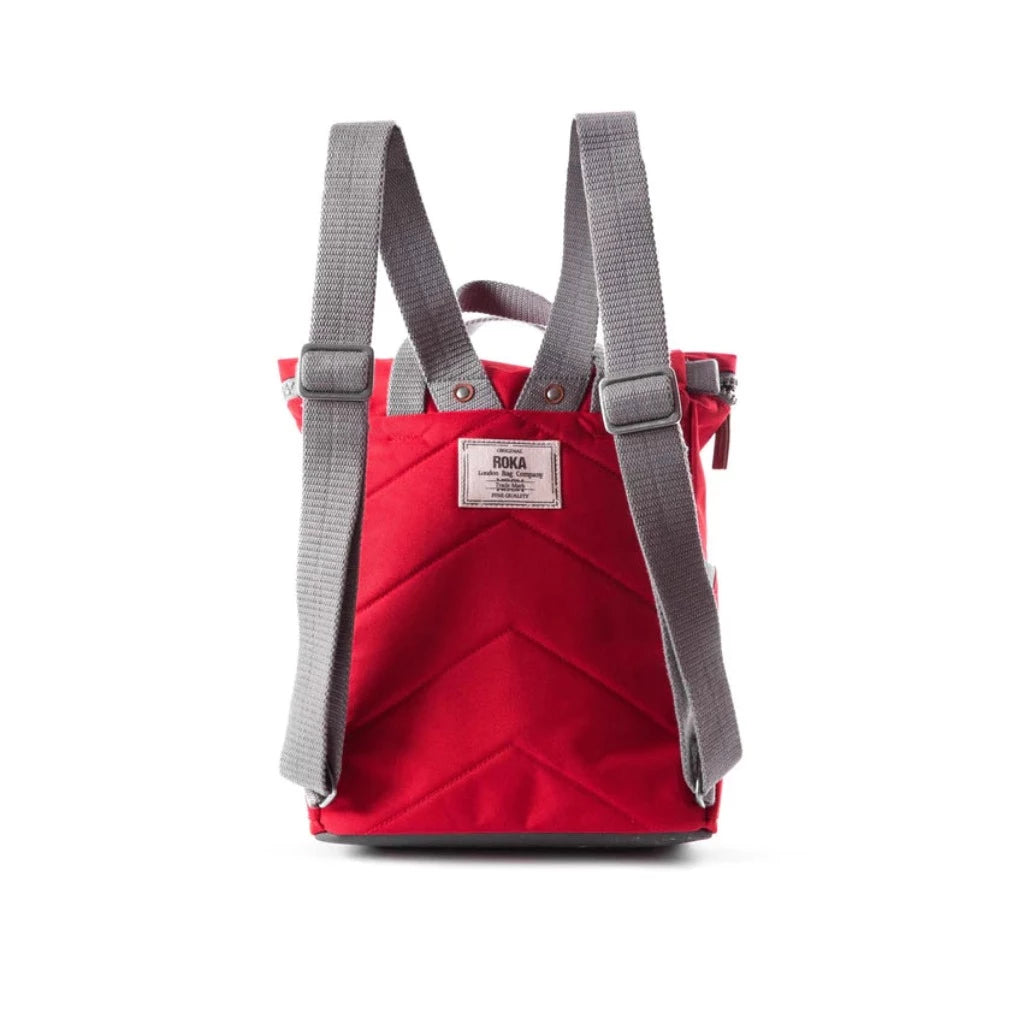 Red quilted backpack with gray straps. The backpack features a small label with the brand name.