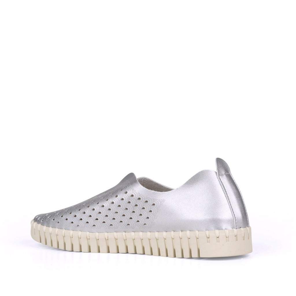 Silver leather slip-on shoe with cream-colored textured sole and patterned cutouts.