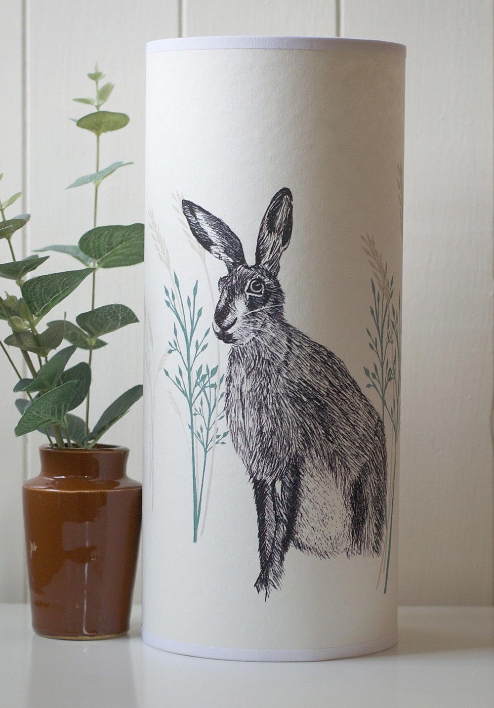 Cream-colored lampshade featuring a black and white illustration of a hare amidst stylized grasses.