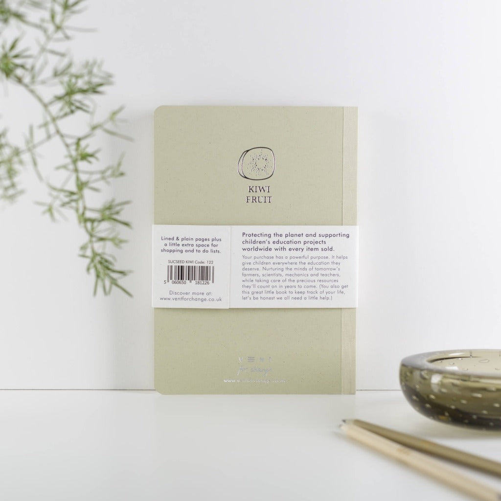 Light beige notebook with "Kiwi Fruit" logo; lined and plain pages; supports children's education projects.