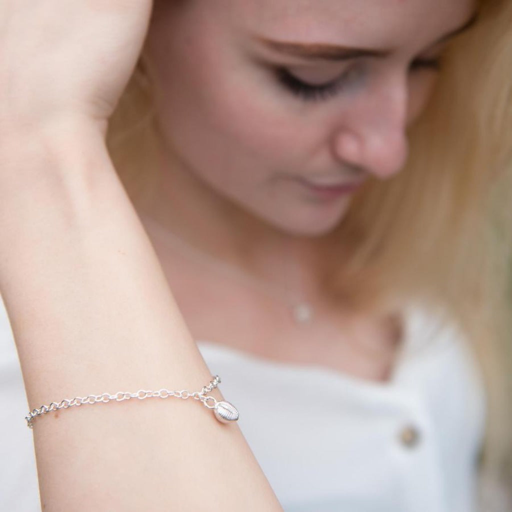 Silver chain bracelet with a small shell charm.