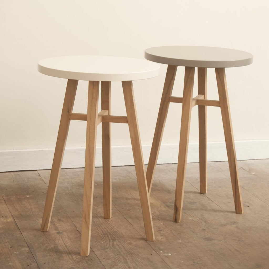 Two round side tables with light wood legs and round tops in white and gray.