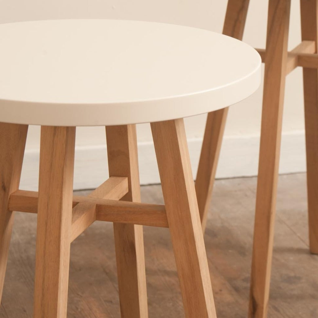 Round side table with off-white top and light wood legs.