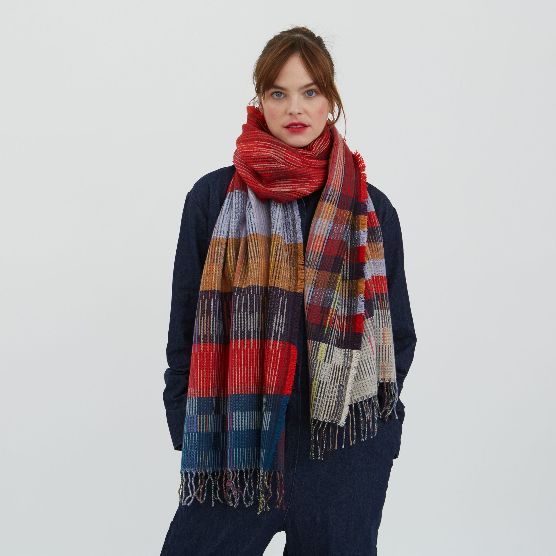 Red, blue, and beige plaid woven scarf with fringed edges.
