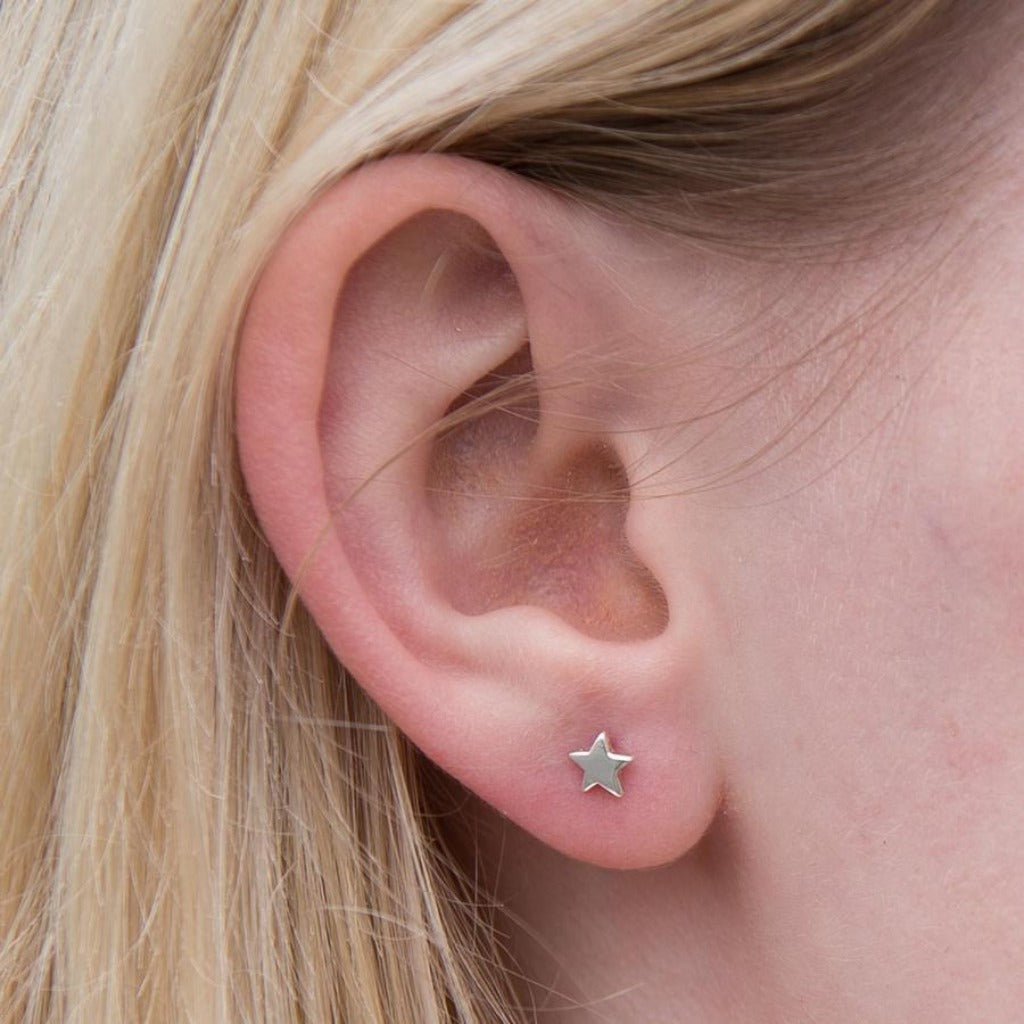 Small silver star stud earring in a pierced ear.