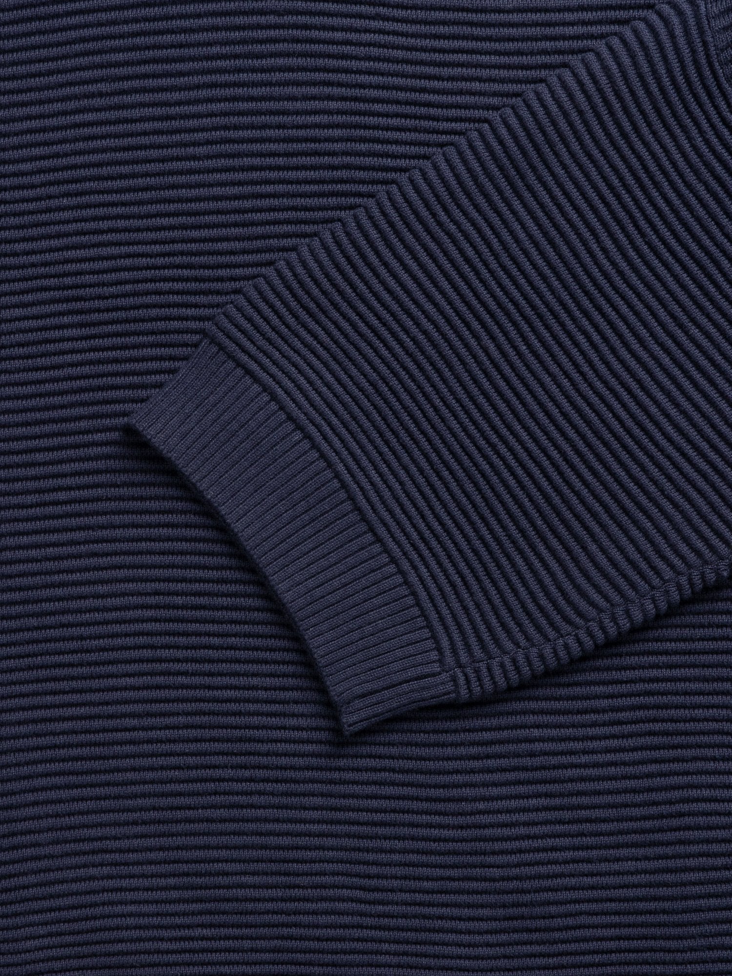Close-up of navy blue ribbed knit fabric, showing texture and detail of the knit stitch.