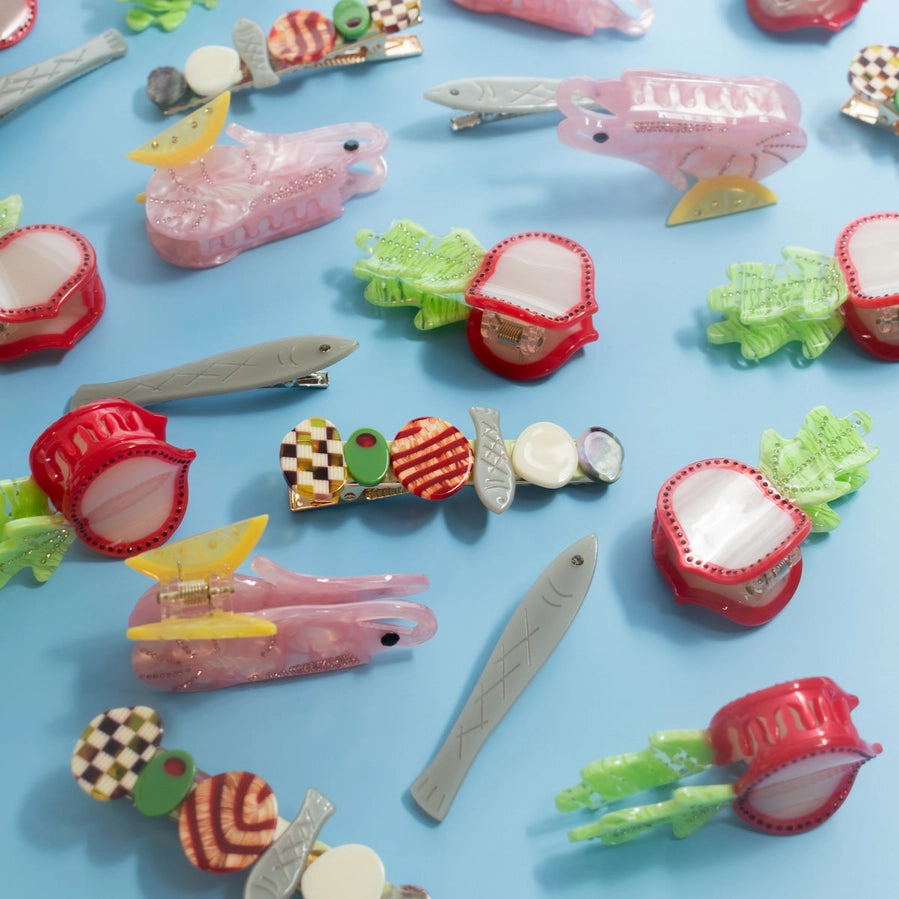 A display of multiple colorful food themed hair clips against a blue background