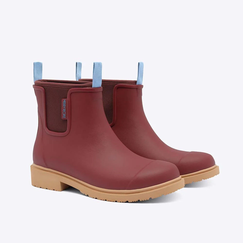 Pair of red rubber boots with beige soles on a light gray background