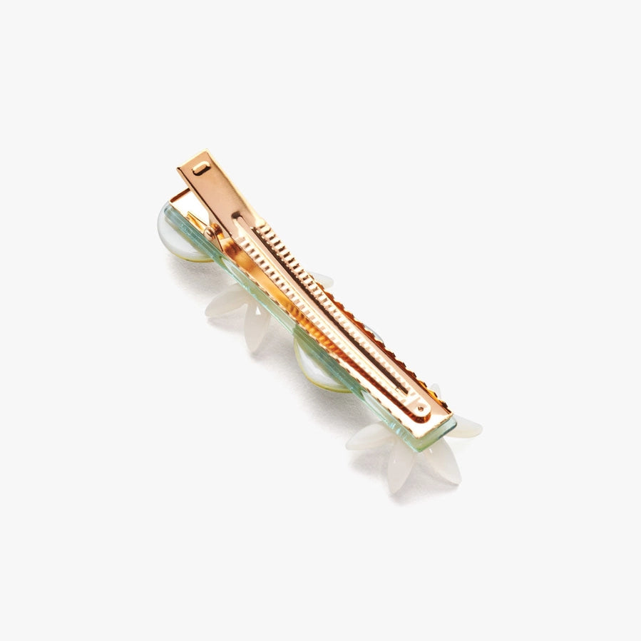 The reverse side of a gold hair clip with floral design on a white background