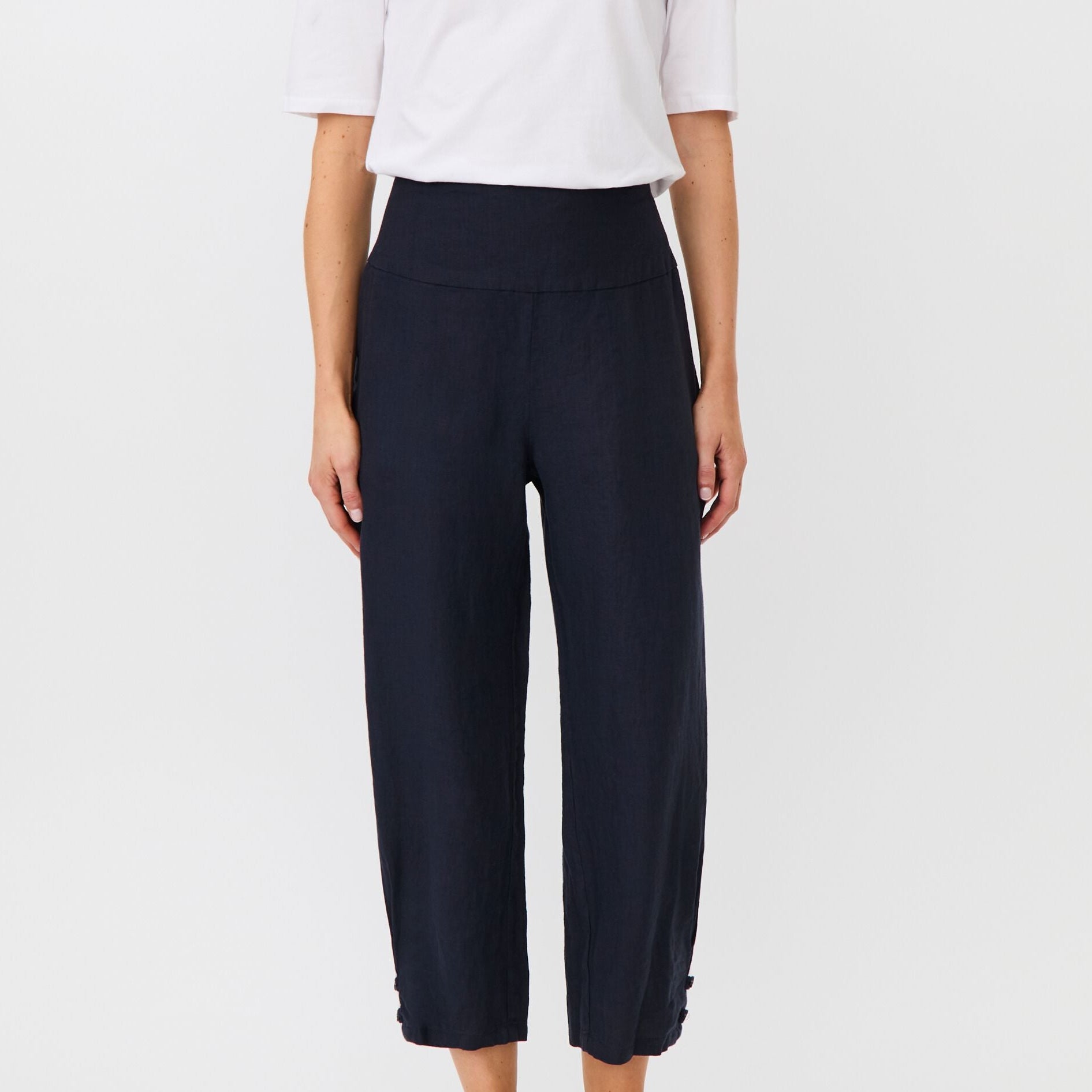 Person wearing navy wide-leg pants and a white top on a light gray background