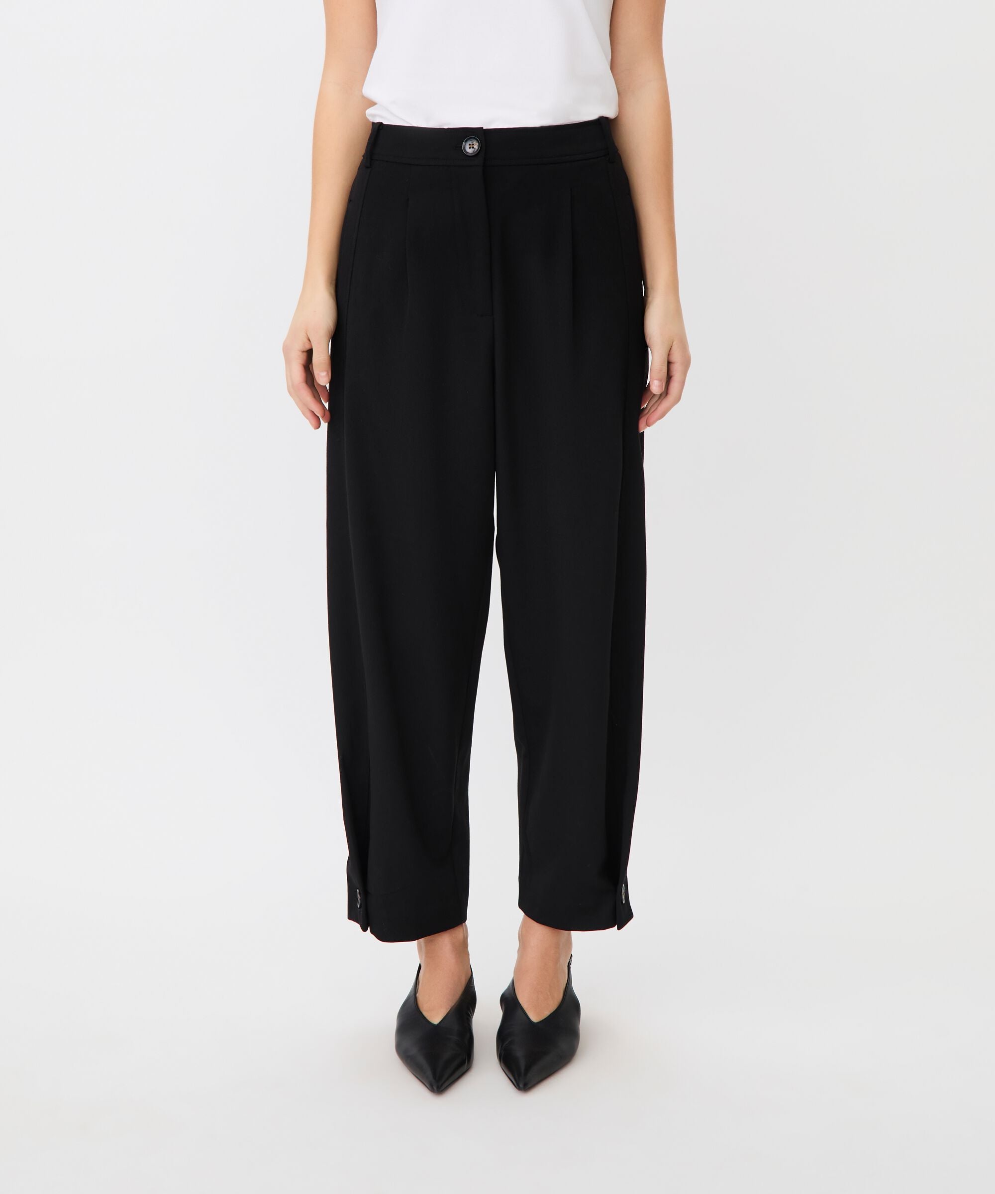 Person wearing black wide-leg pants on a white background