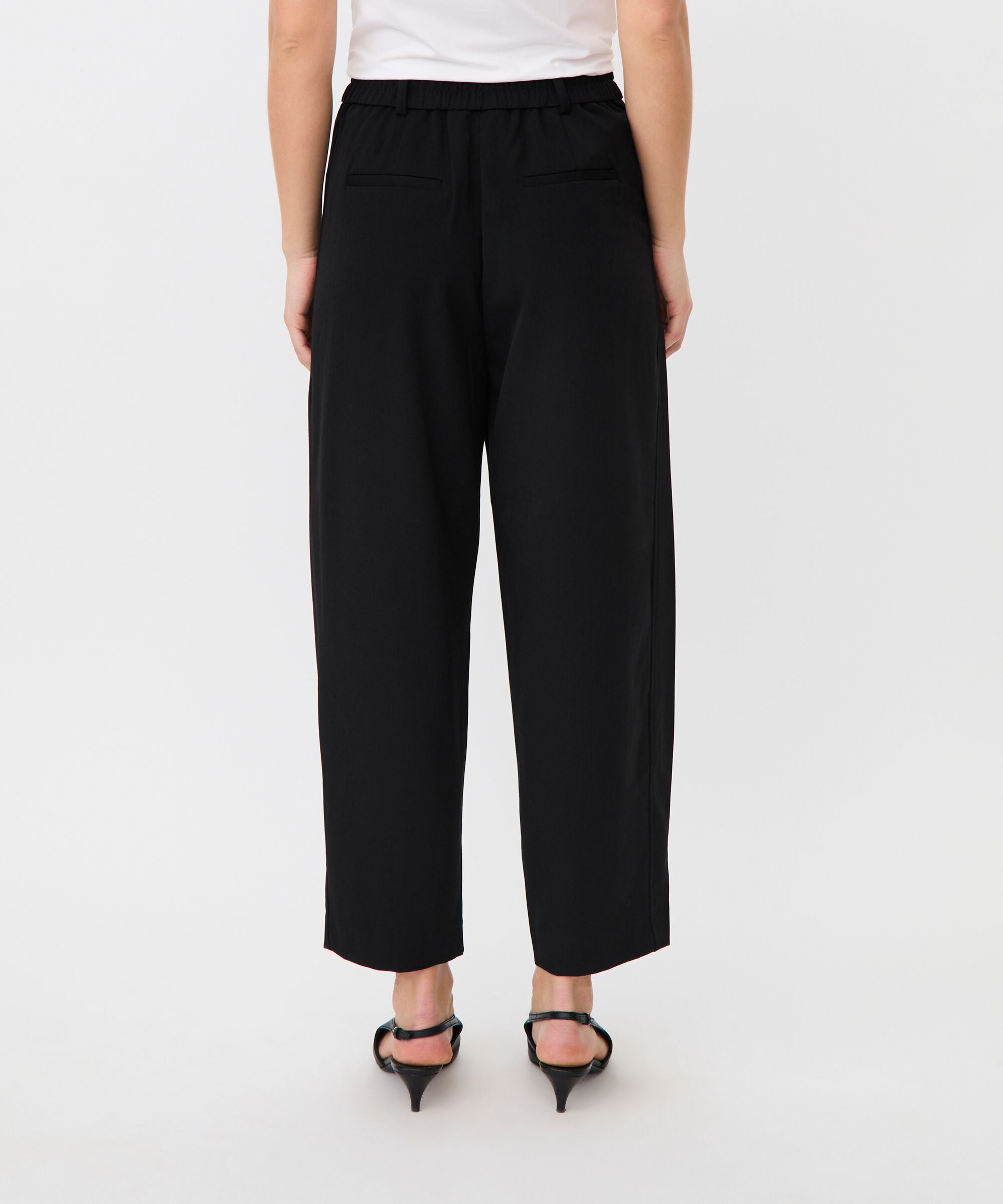 Person wearing black wide-leg pants on a white background