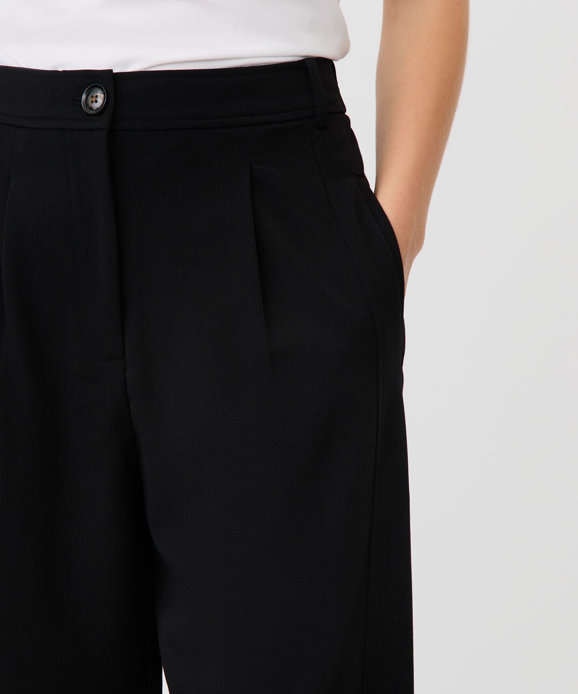Black pants with a button detail on a white background
