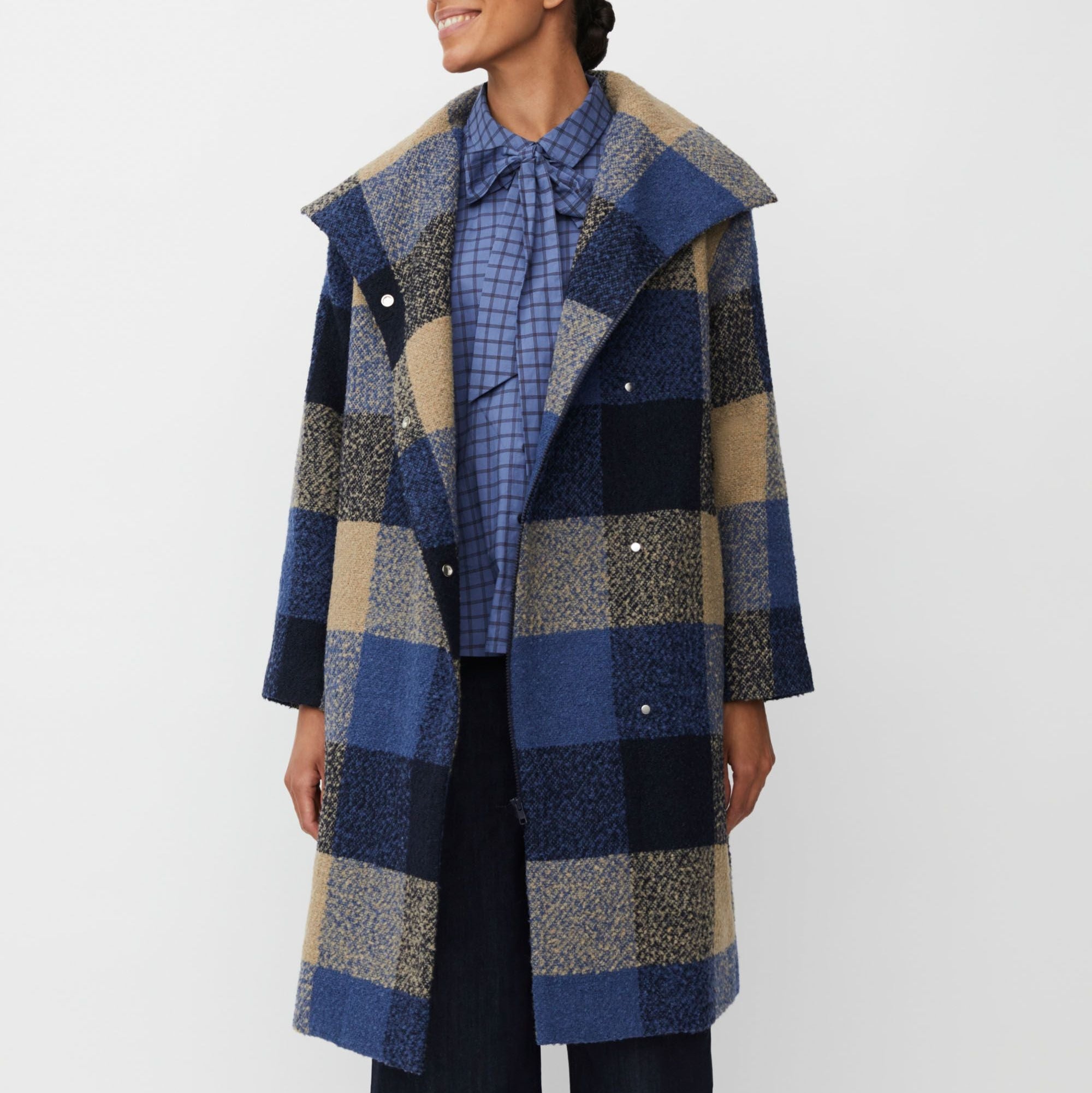 Woman wearing a checkered coat with a white background