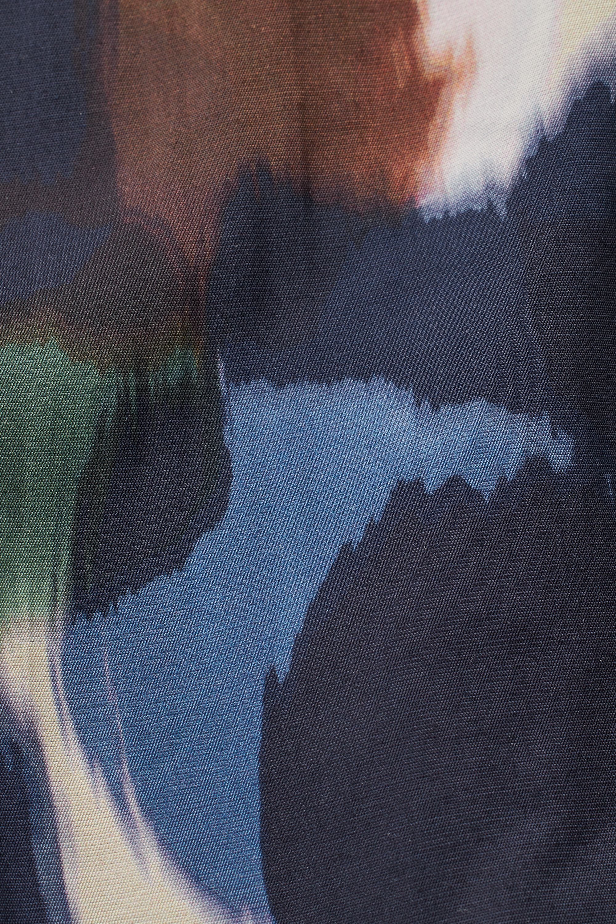 Close-up of dark navy fabric with an abstract print featuring shades of blue, brown, and green in a watercolor-like style.