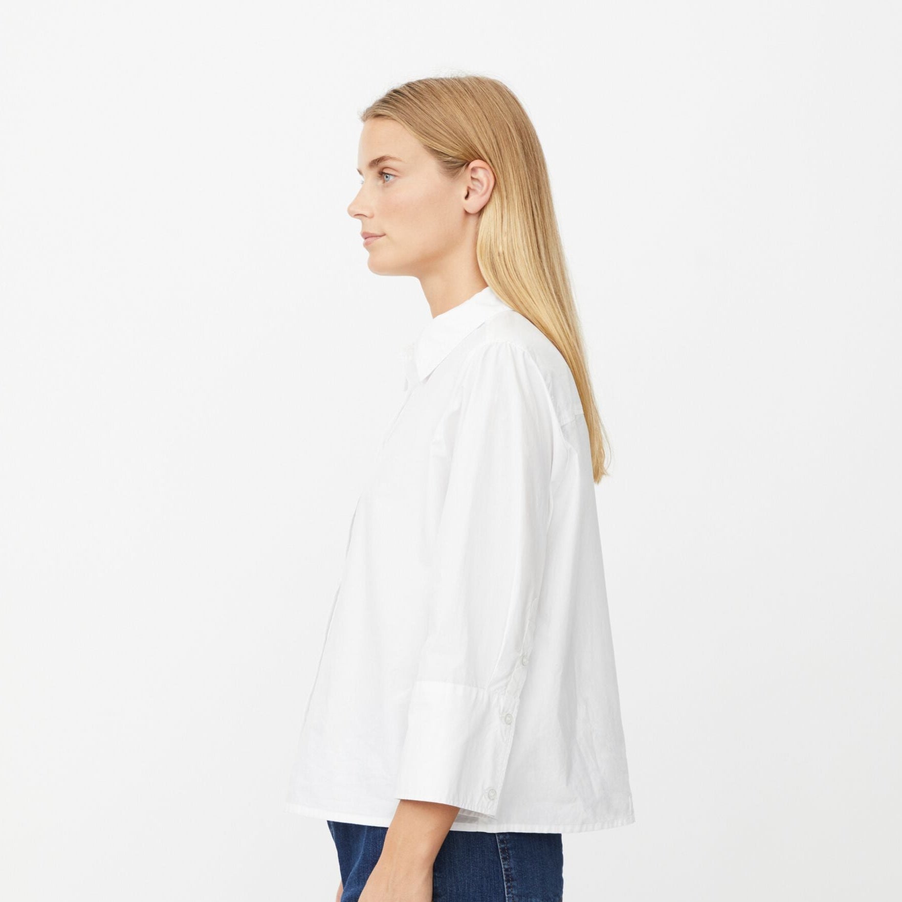 Woman wearing a white blouse and blue jeans on a white background