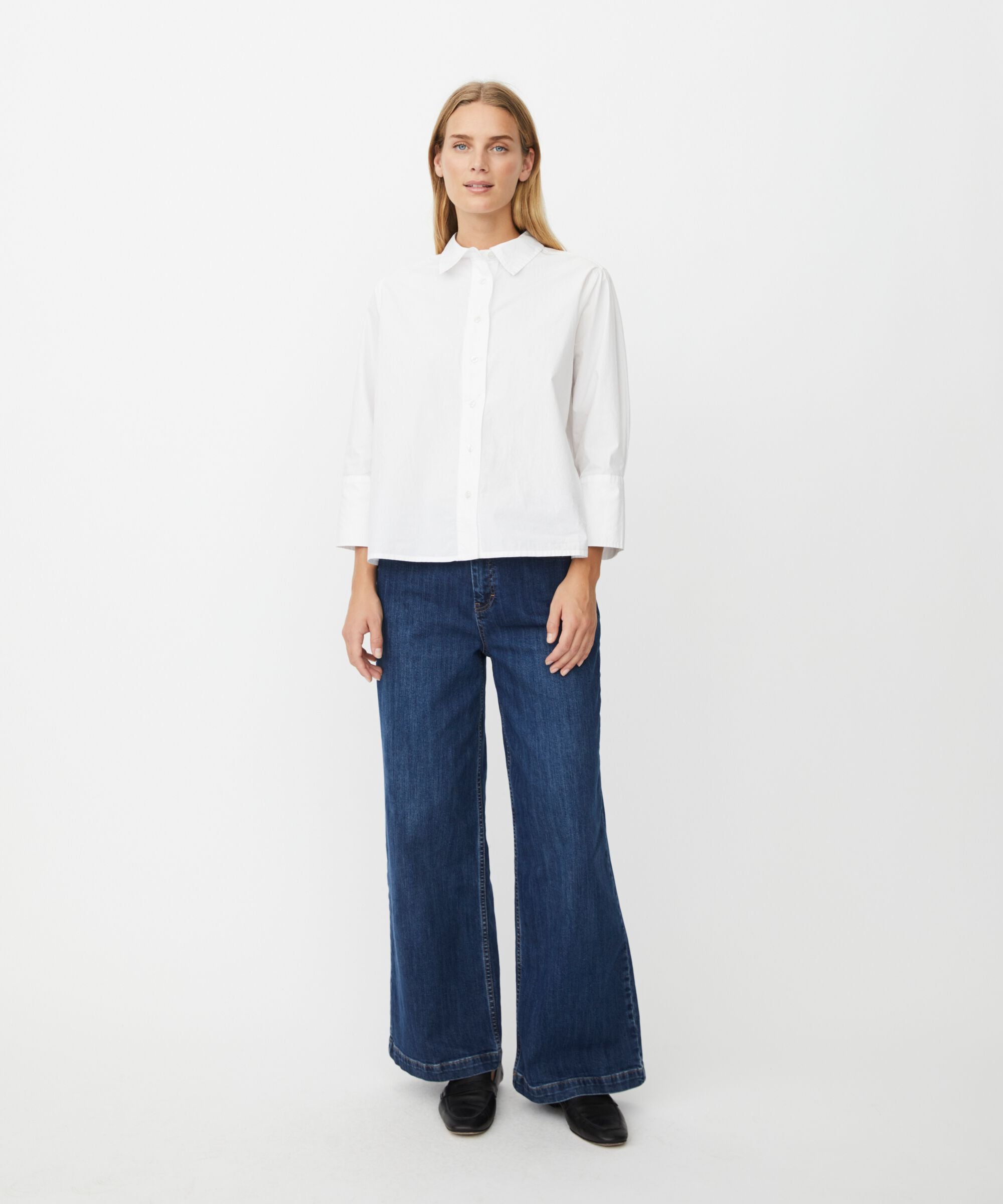 Woman wearing a white shirt and blue jeans on a white background