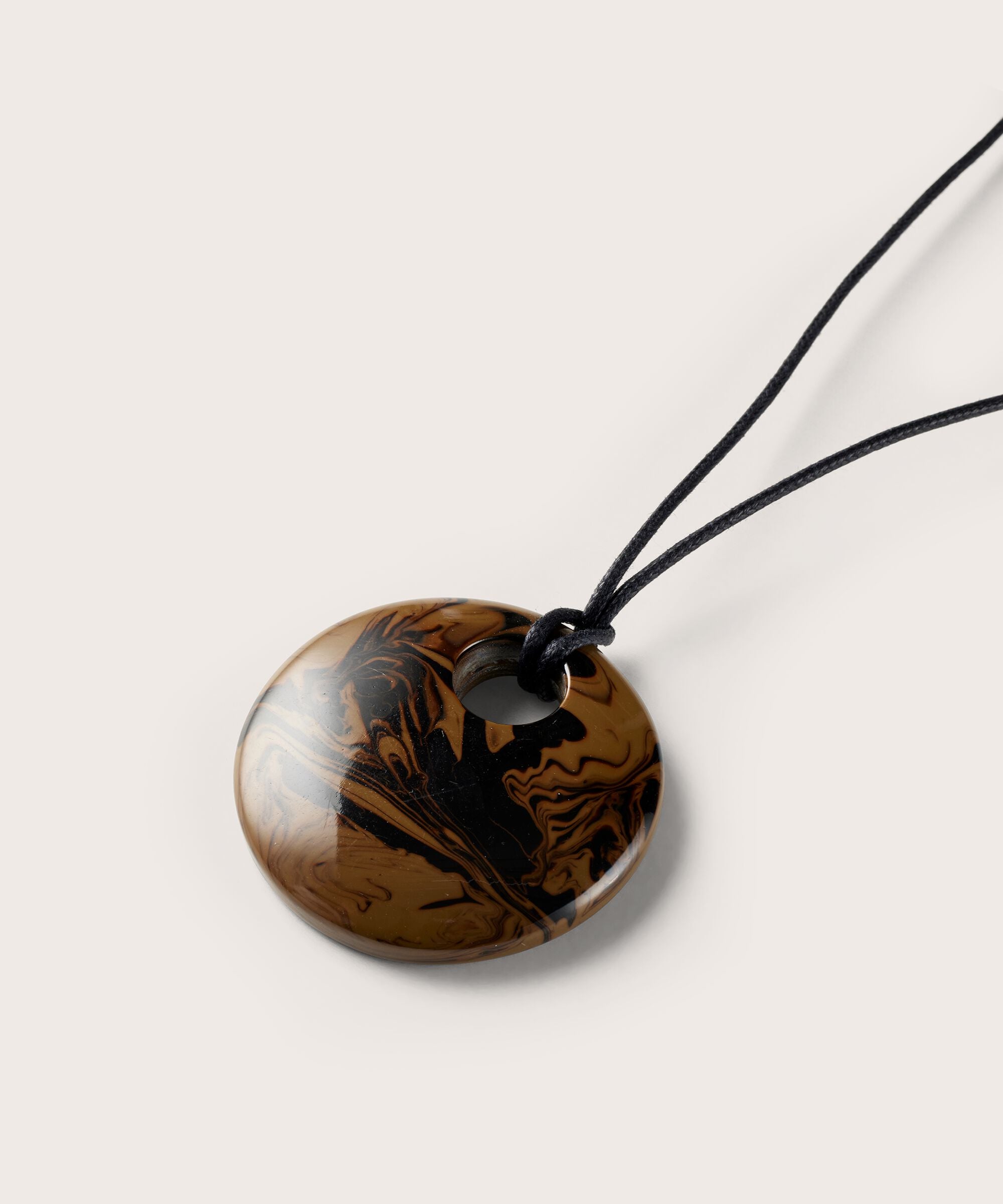 Brown pendant with black floral design on a white background