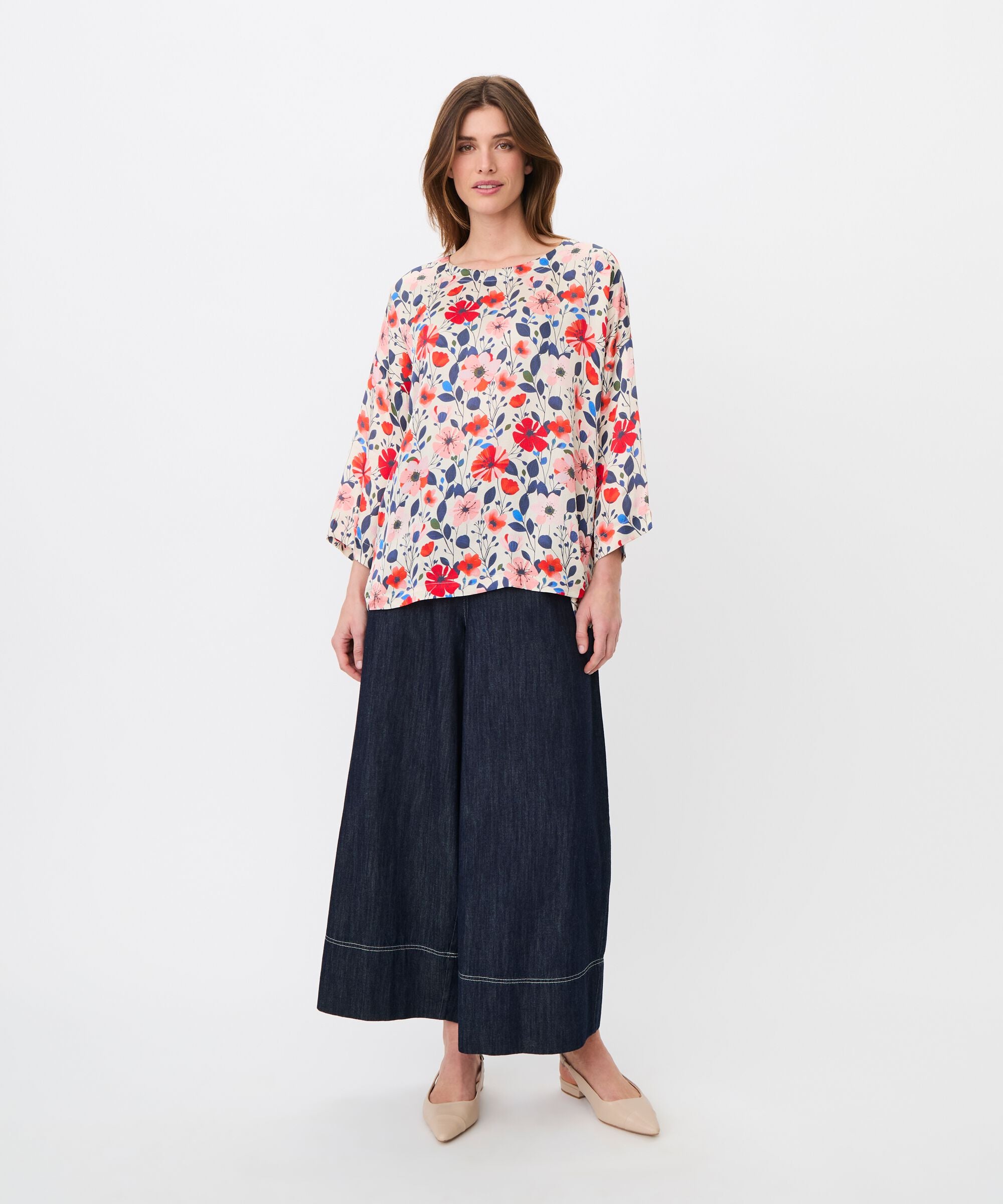 Woman wearing a floral blouse and denim skirt on a white background