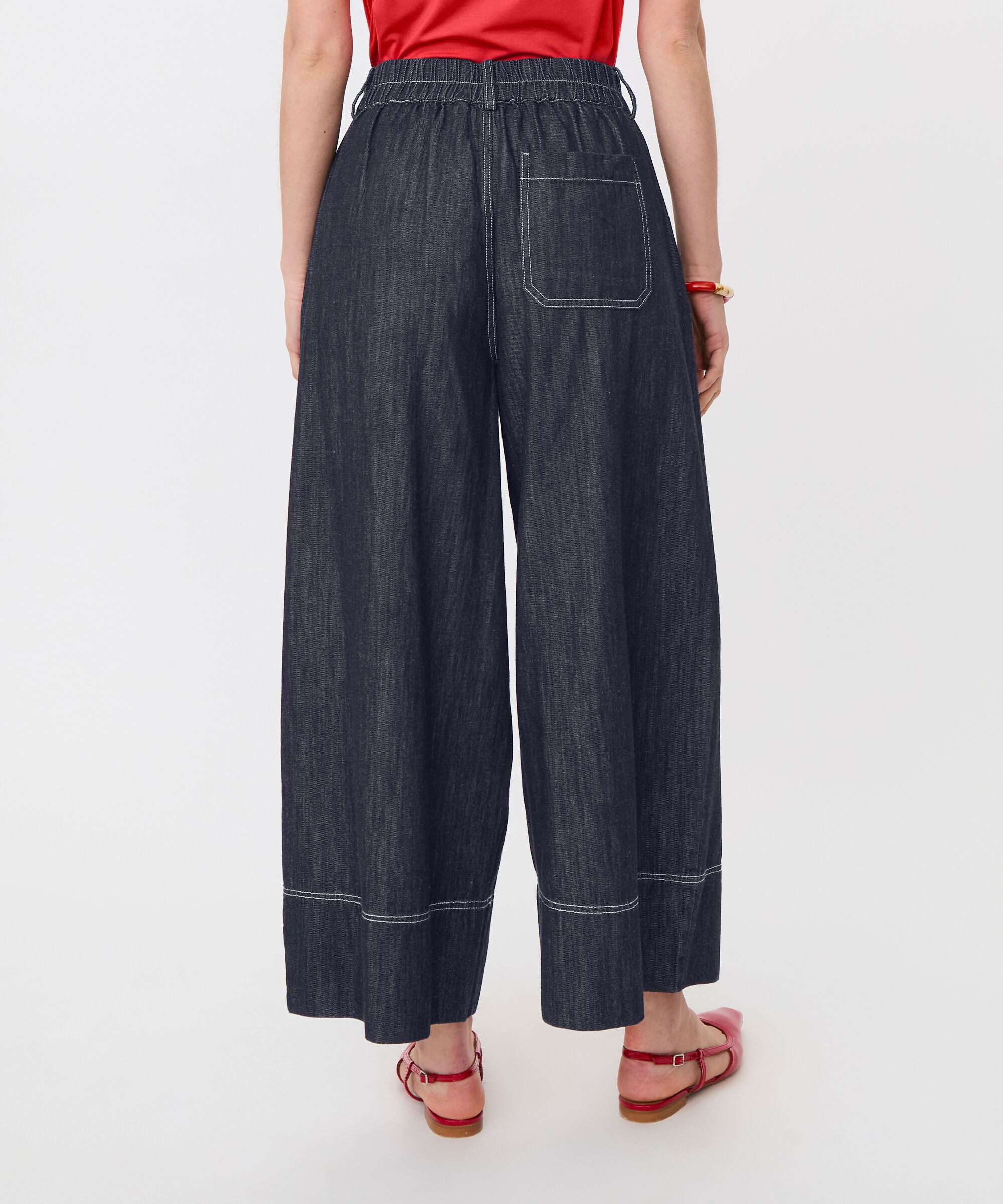 Person wearing dark blue wide-leg jeans on a white background