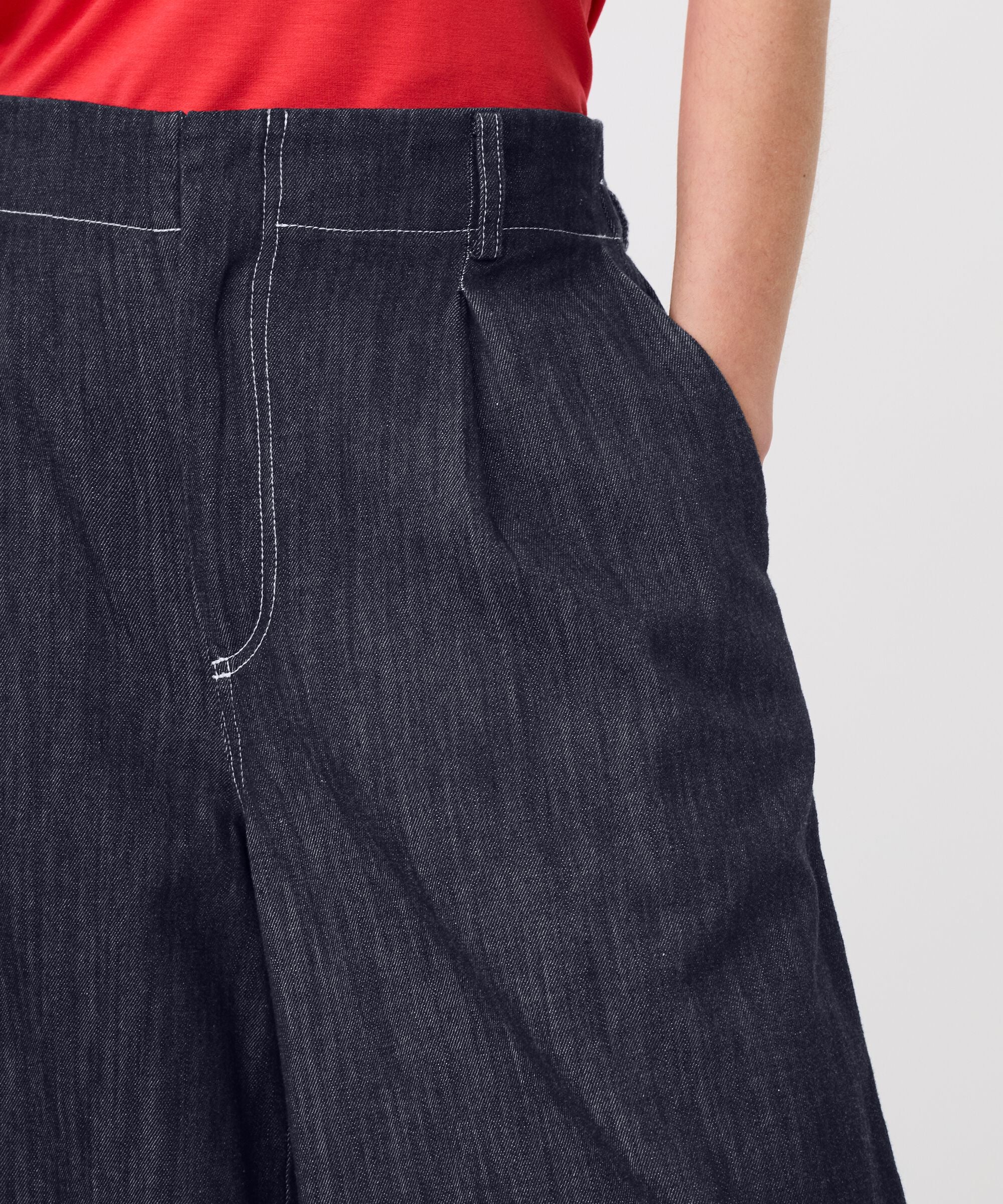 Dark blue denim pants worn by a person on a light gray background