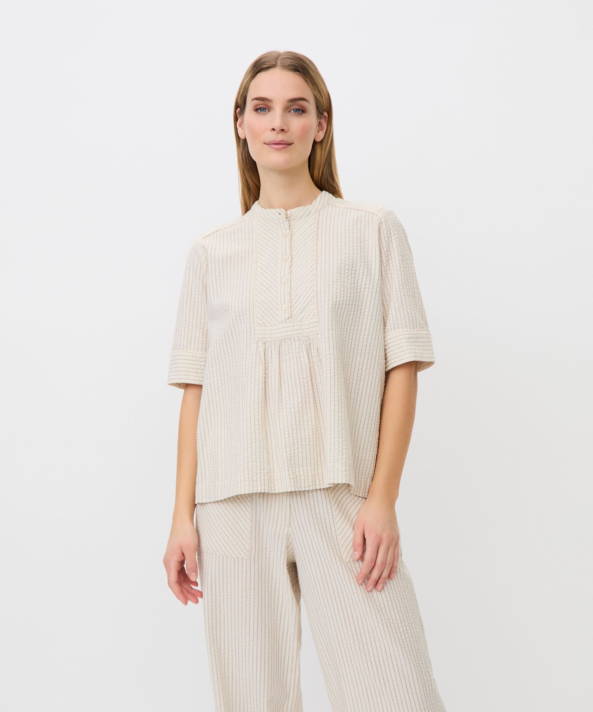 Woman wearing a beige blouse and pants on a white background